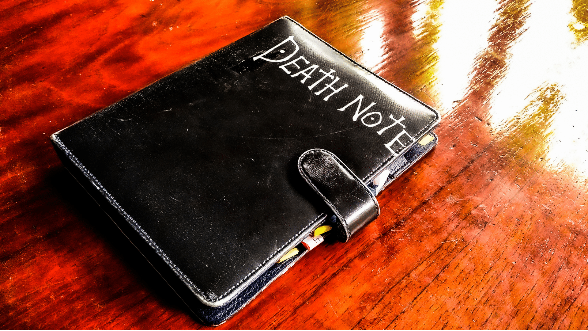 a black note book with the words death note lies on a brown table